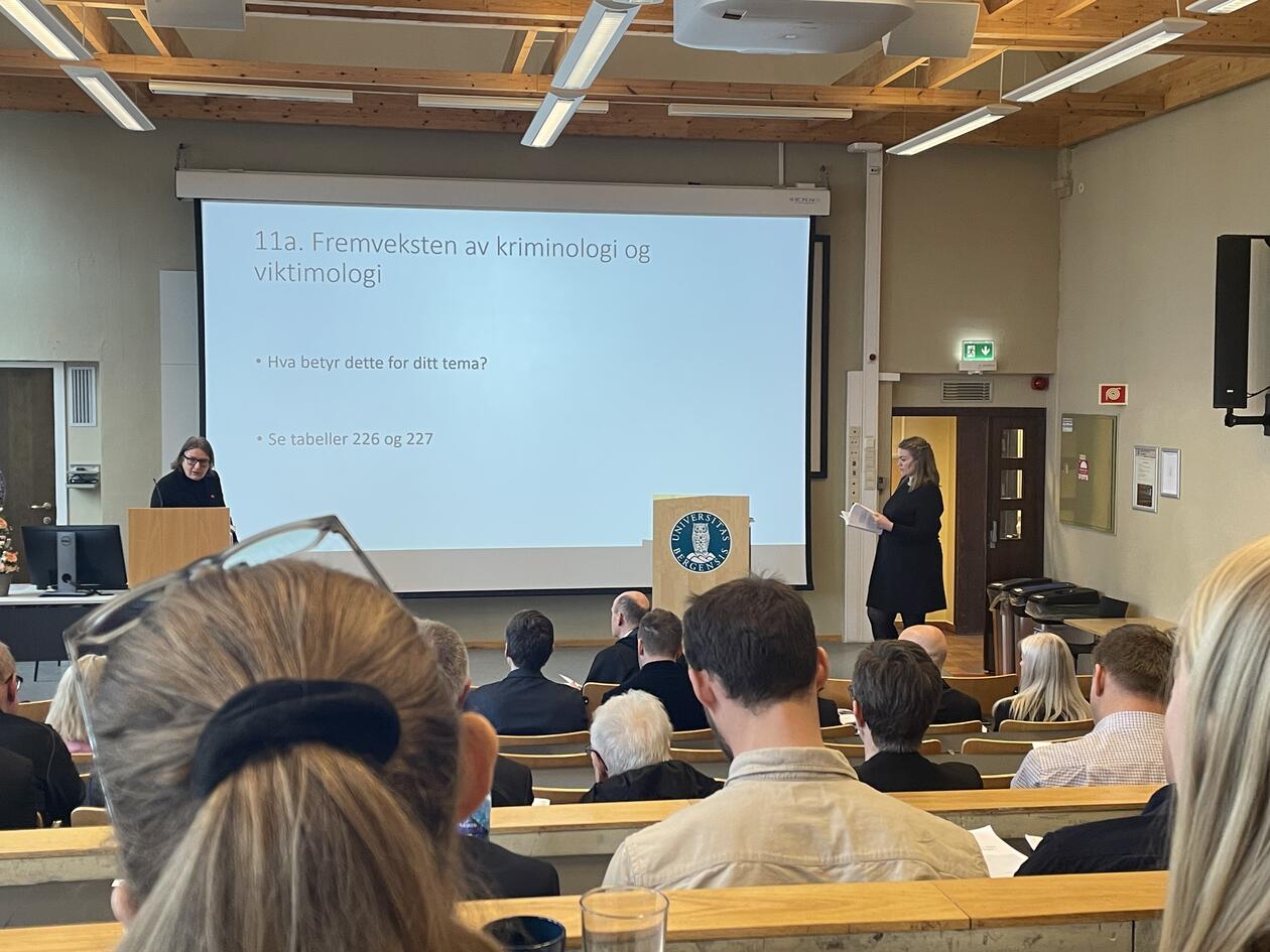 Bilde fra bakerst i forelesningssal av disputant og opponent som diskuterer