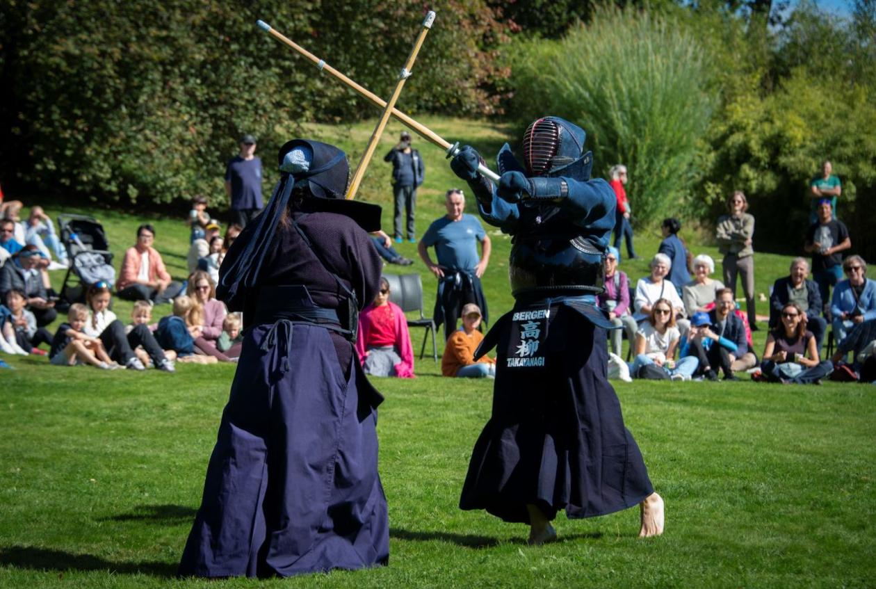 To personer som utøver kendo foran en folkemengde på gresset