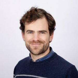 A man with short brown hair and a dark sweater