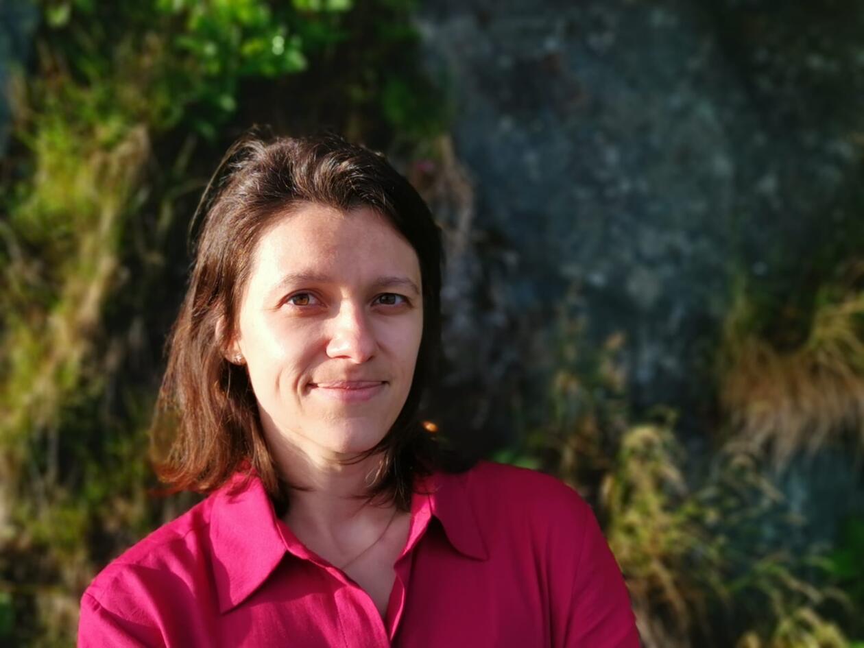 Portrait photo of a young woman with medium long hair in a pink shirt