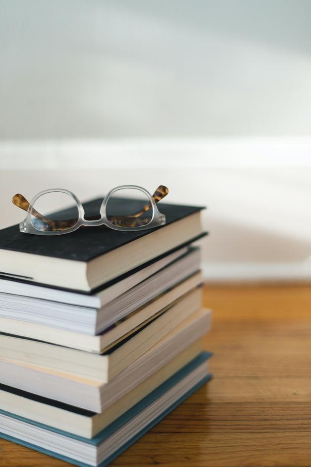 Stabel av bøker med et par briller liggende på toppen