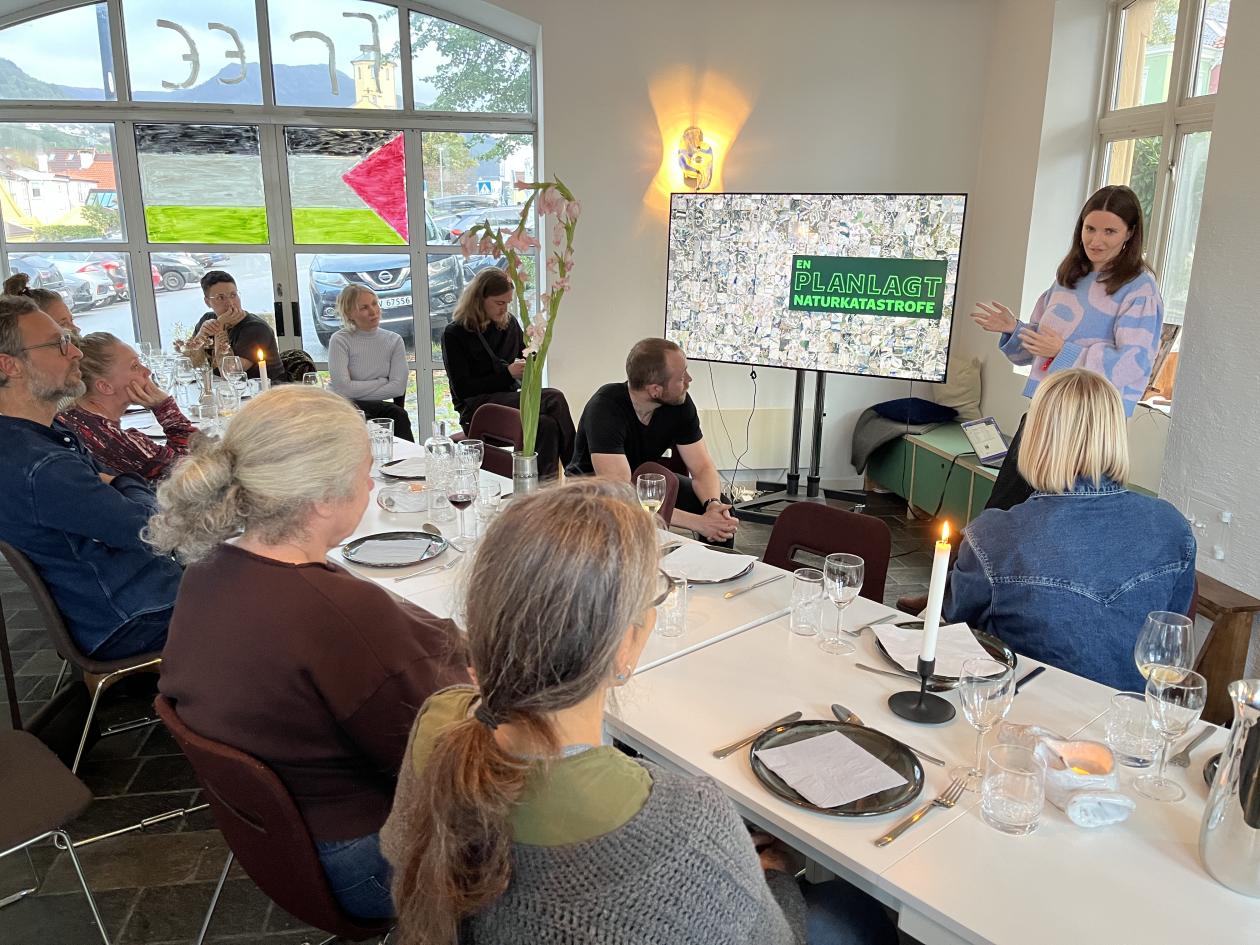 A group of people seated around a table with one person giving a presentation