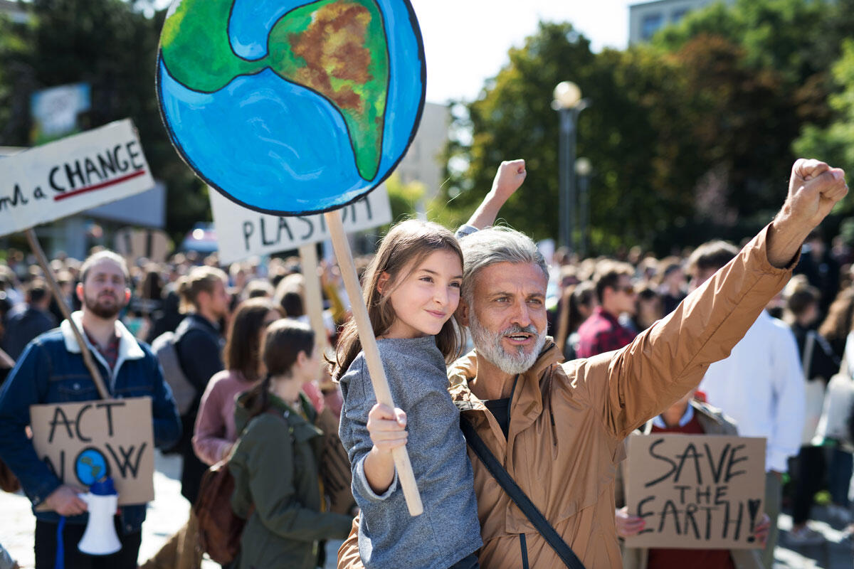 Ung jente og eldre mann protesterer sammen i en større klimademonstrasjon