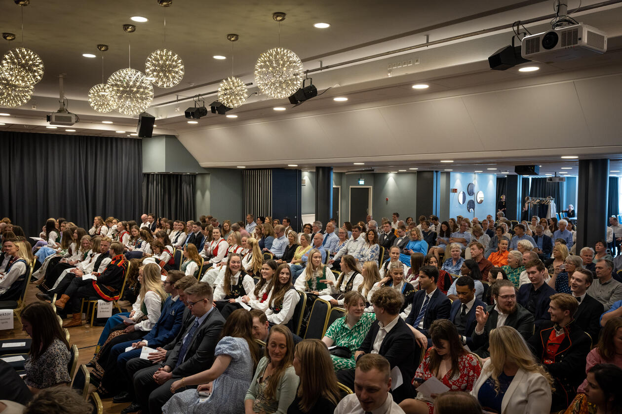 Fullsett sal med studentar og foreldre i finstas