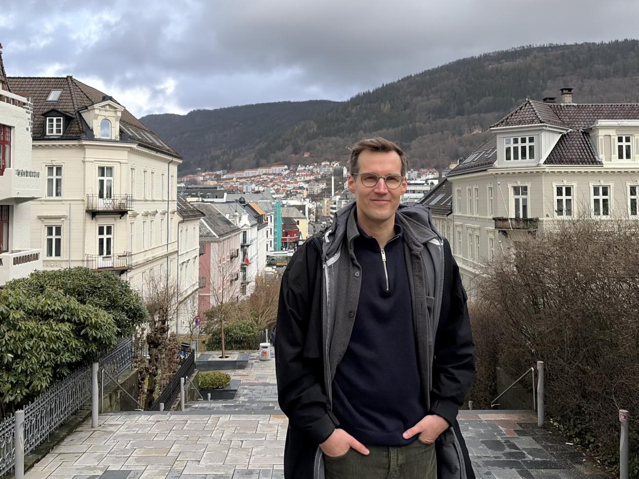 Portrettbilde av Lukas Skiba med bybildet Bergen i bakgrunnen