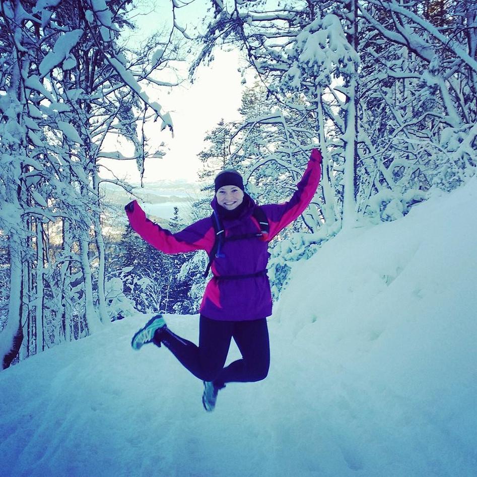 Ung kvinne som hopper i snøen