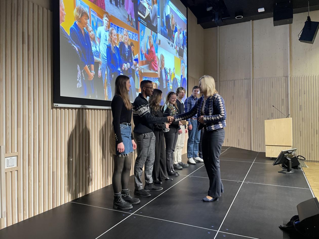 Sigrunn Eliassen deler ut prisen til en rekke studenter i Storsalen.