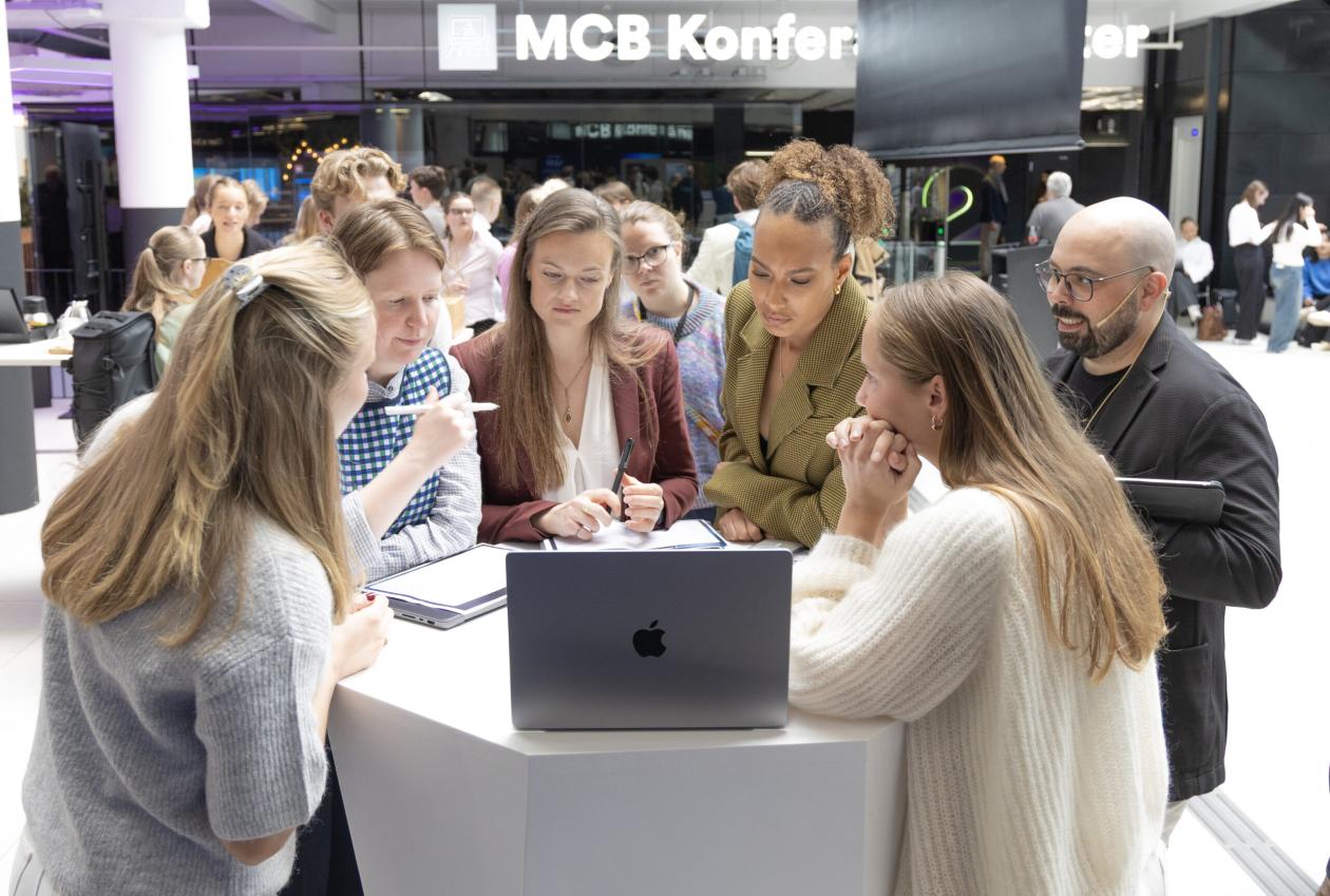 Studentar er samla rundt eit bord og ser på ei teknisk løysing.