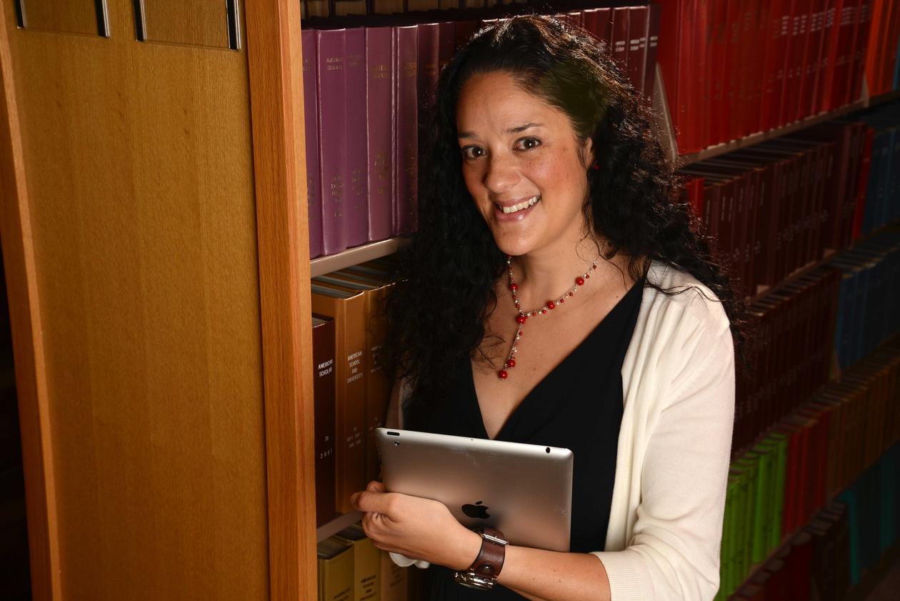 Photograph of Mia Zamora holding an iPad in a library.