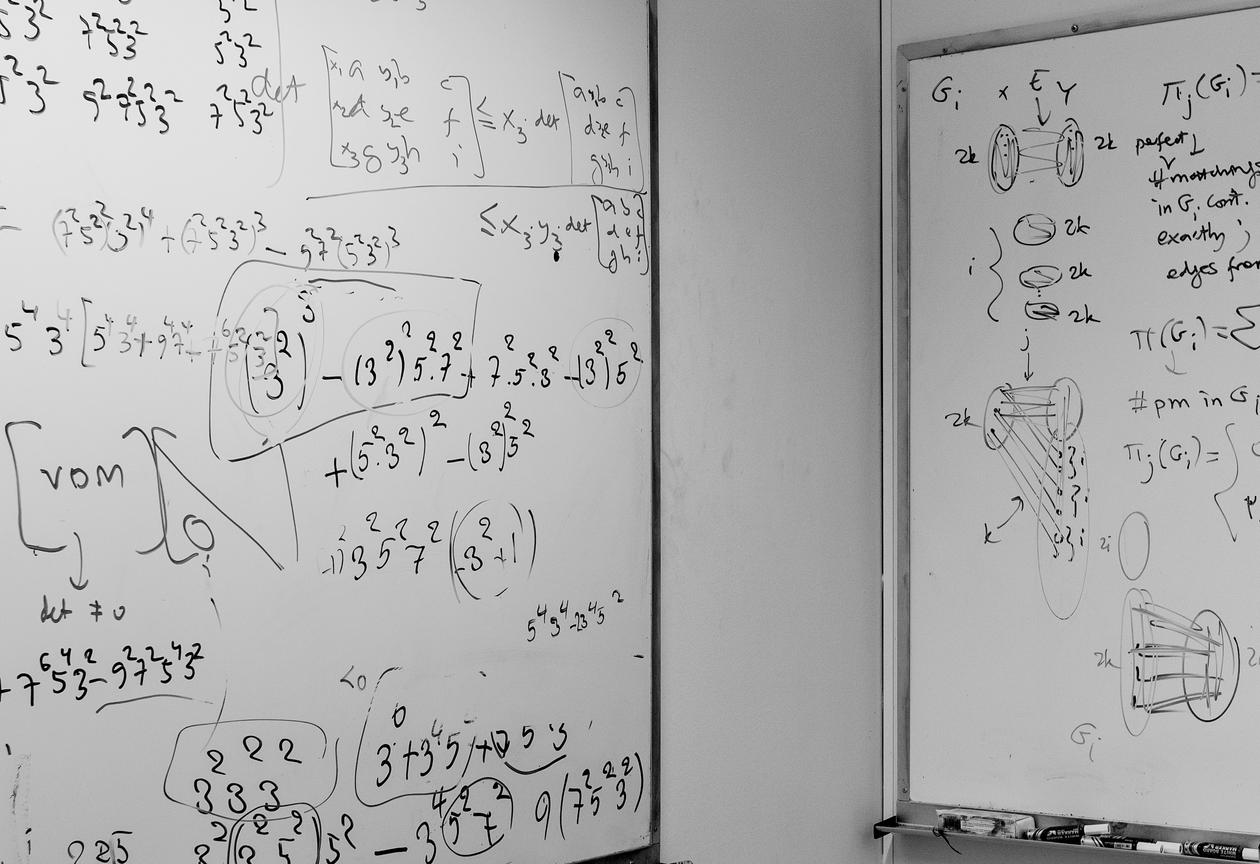 Photo showing two boards full of mathematical riddles, the picture is from the Bergen Algorithms Research Group's offices.