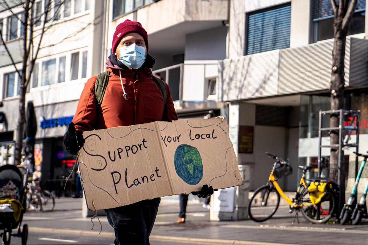 Man holds sign saying "Support your local planet" 
