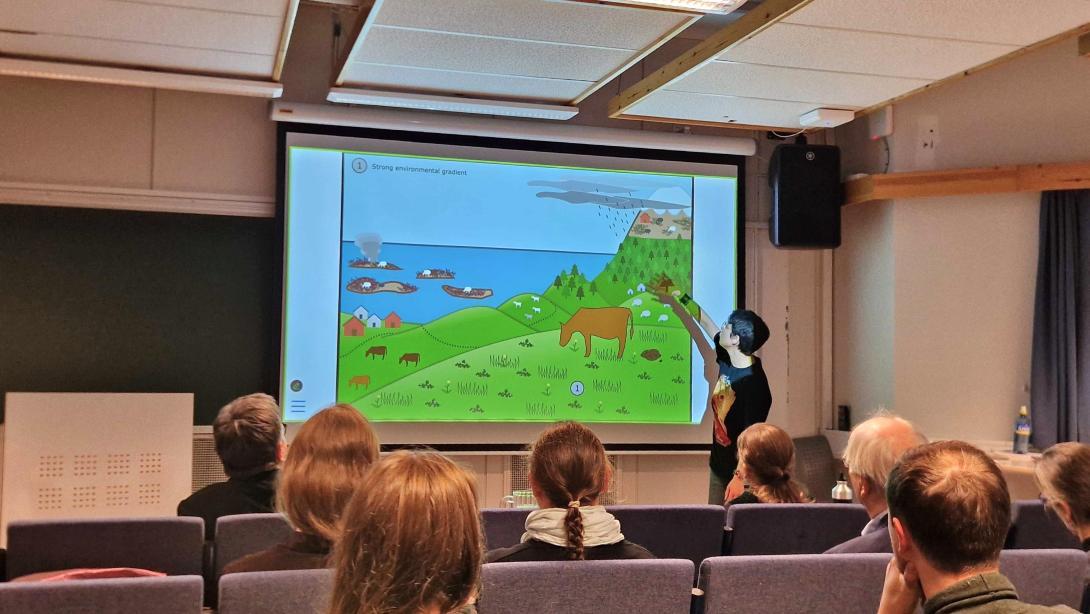 A group of people seated around a table with one person giving a presentation