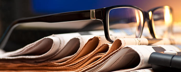 pile of newspapers and a pair of glasses