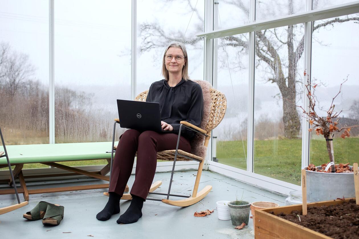 Kirsti Nordstrand sit i gyngestol med laptop og arbeider