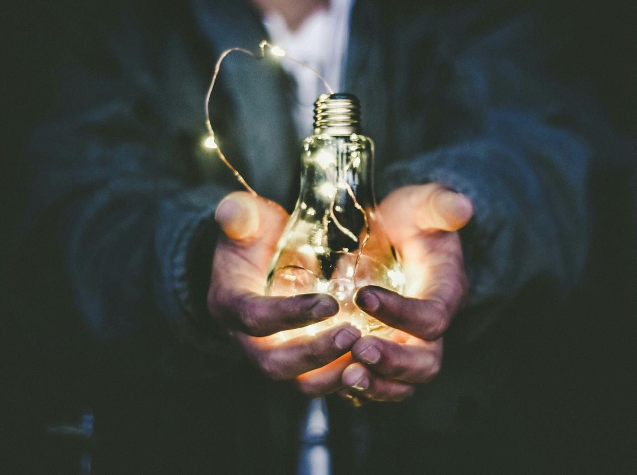 En person holder en lysende glødepære i hendene