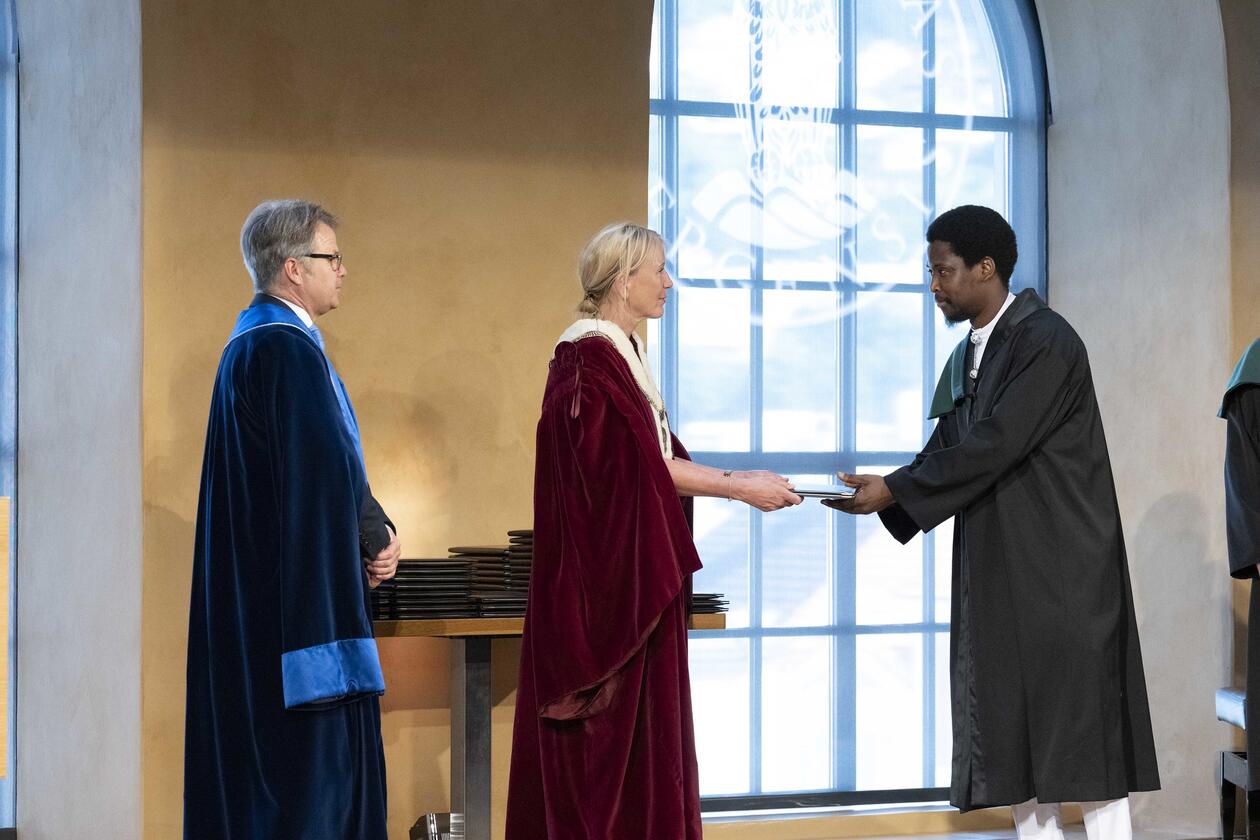Doktorpromosjon i Universitetsaulaen 27.01.2023: Bilde av ny doktor fra Det naturvitenskapelige fakultet som får sitt diplom av rektor og universitetsdirektør