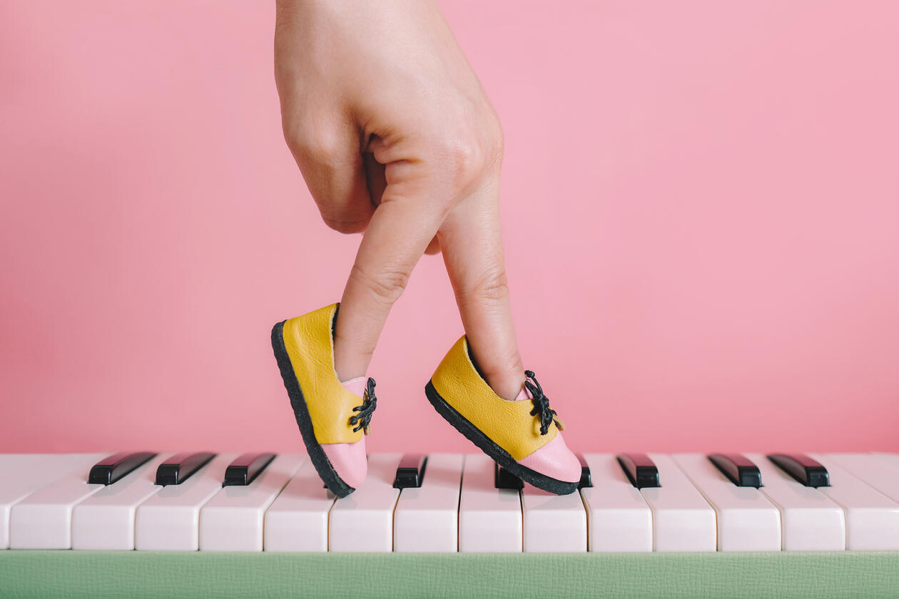 Fingrar med sko som speler på piano