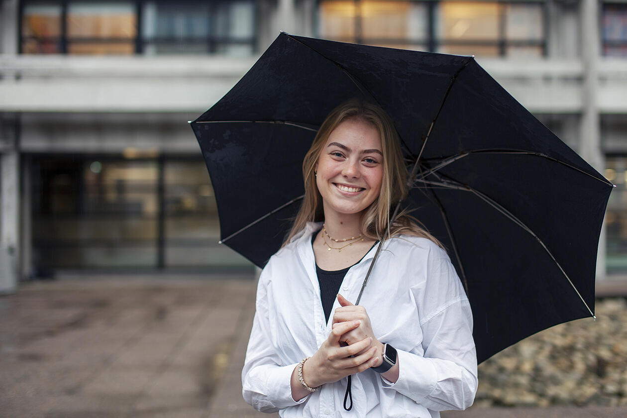 Student Tuva Småland Hagland med paraply forran Realfagsbygget