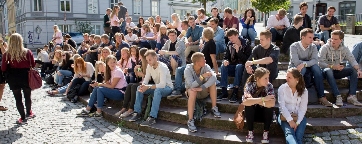 Mange nye studenter sitter i solskinnet utenfor SV-bygget