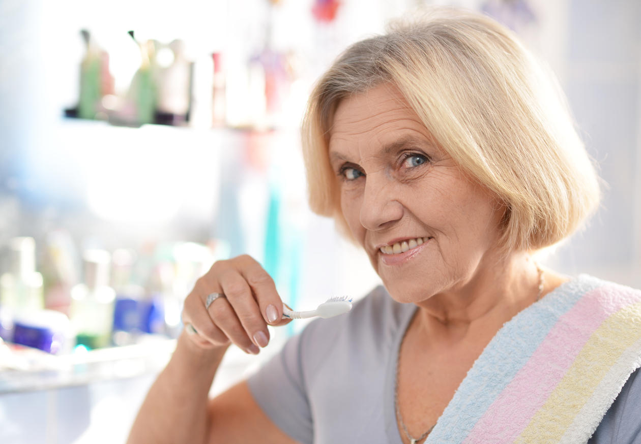 Illustrasjonsfoto av eldre kvinne som puser tennene.