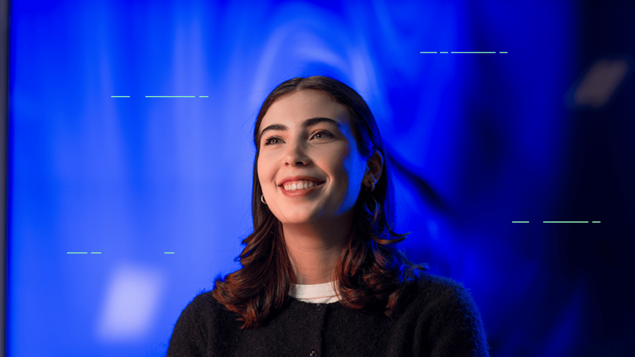 Smilende ung kvinne med blå bakgrunn.