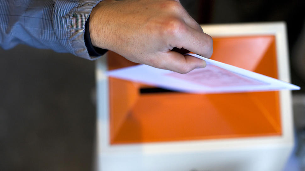 Bilde av hånd som slipper stemmeseddel i valgurne