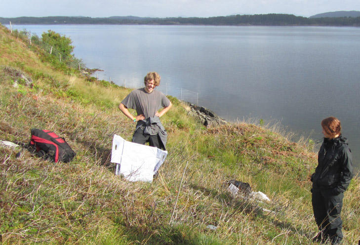 Two students surveying heathland vegetation next to a fjord