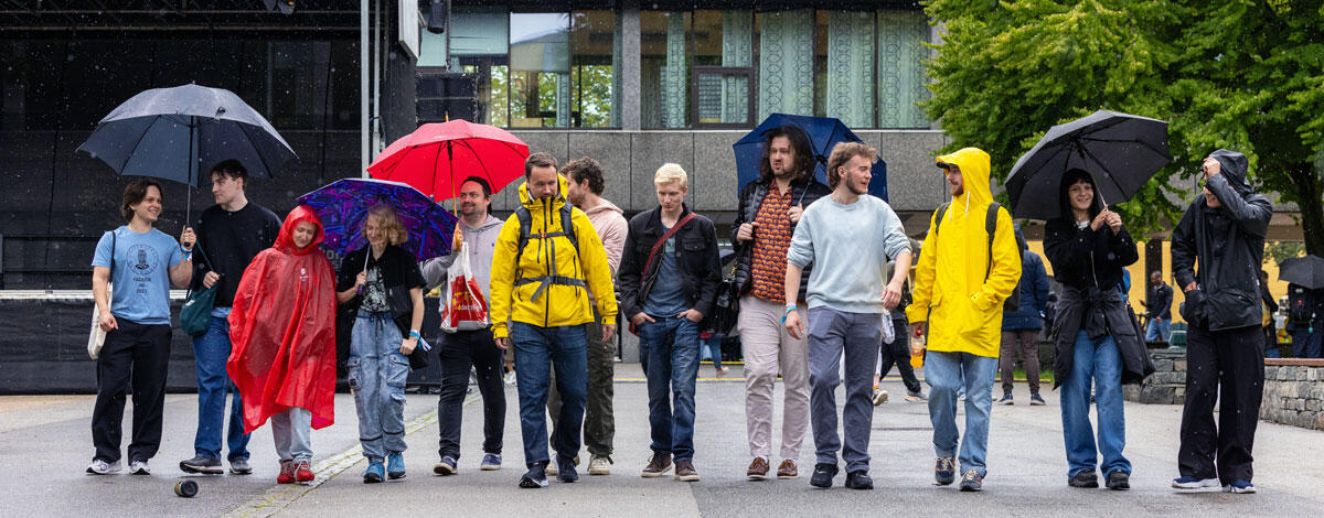 En rekke studenter med regntøy og paraplyer