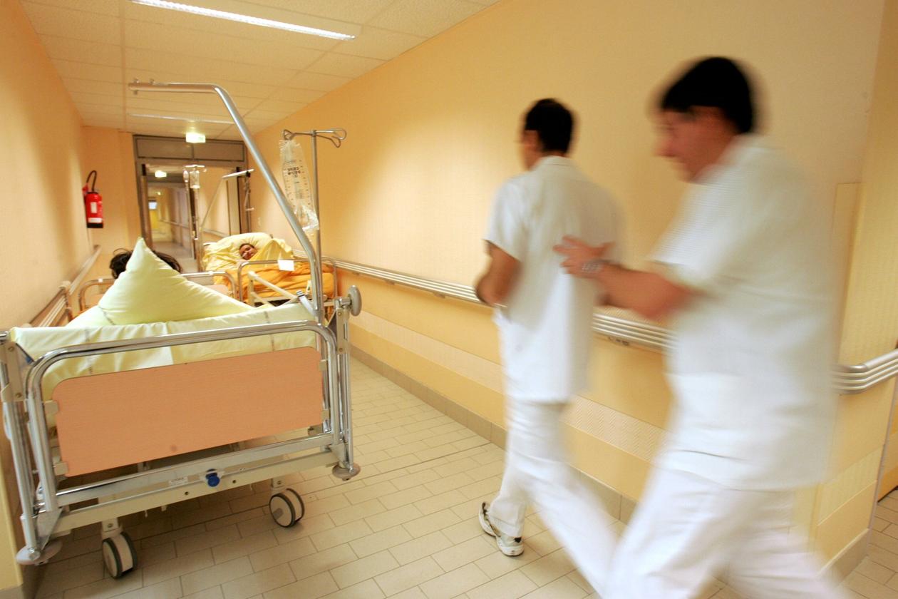 Bilde fra et sykehus hvor to ansatte haster forbi to sengeliggende korridorpasienter