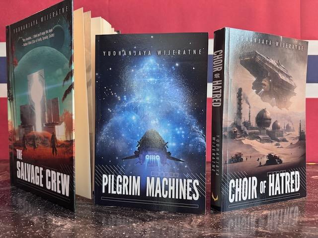 Photo of three books: The Salvage Crew, Pilgrim Machines and Choir of Hatred