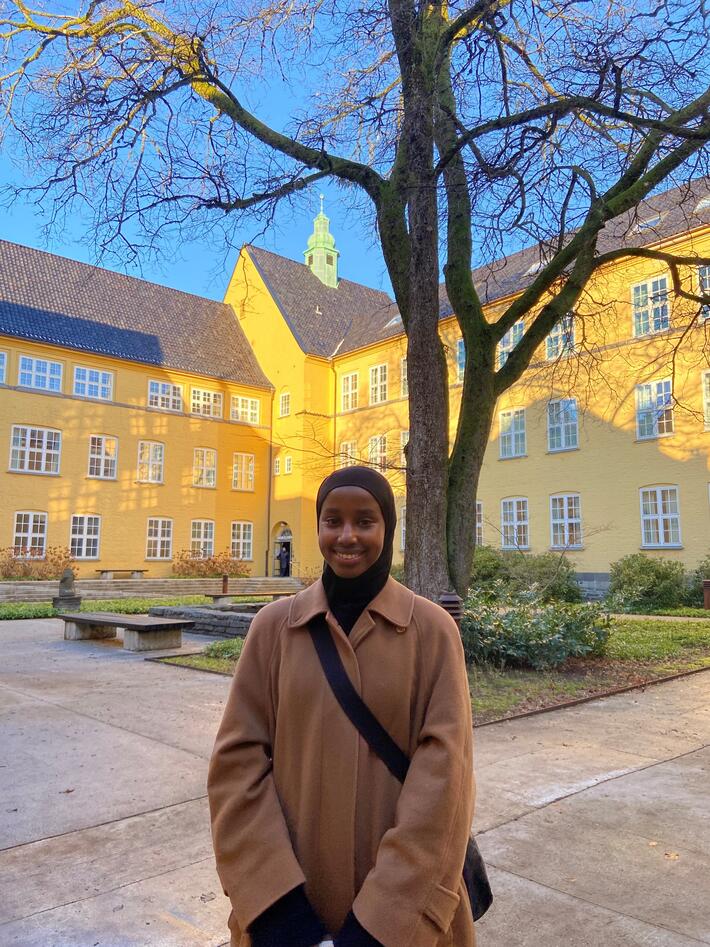 Bilde av ung kvinne med Sydneshaugen skole i bakgrunnen