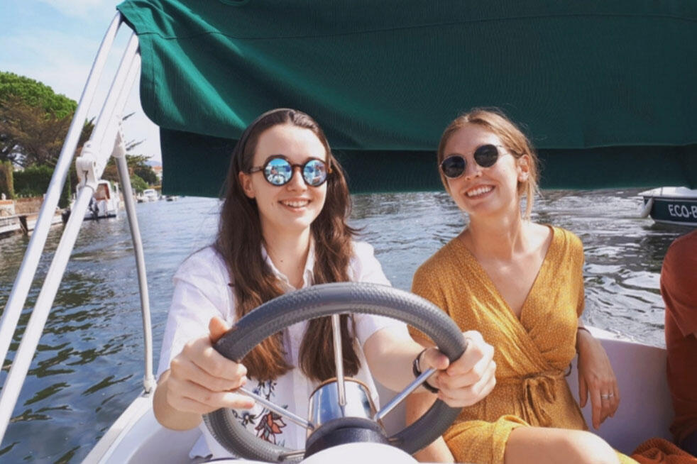 To damer med solbriller på kjører båt en sommerdag utenfor Barcelona