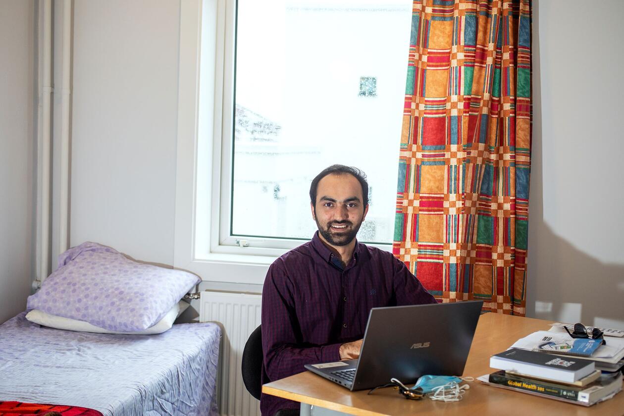 Mudasar Iqbal sit ved skrivebord på hybel og arbeidar på laptop.