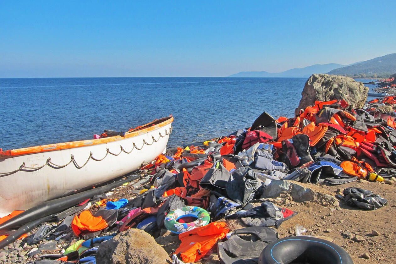 Strandet båt ved strand omgitt av redningsvester og migranters eiendeler