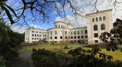 The University Museum of Bergen pictured slightly obscured by branches from surrounding trees.