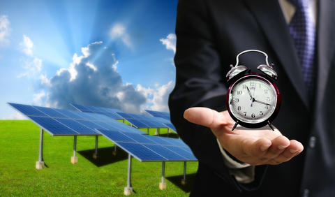 Solcellepaneler og en mann med en klokke