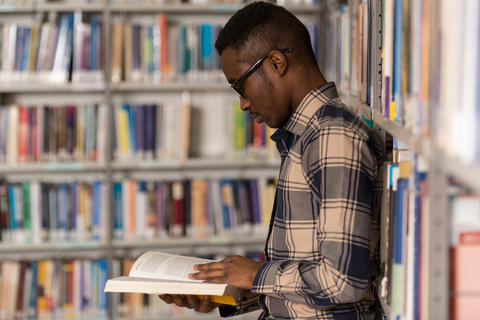 African man in library seen in profile reading a book