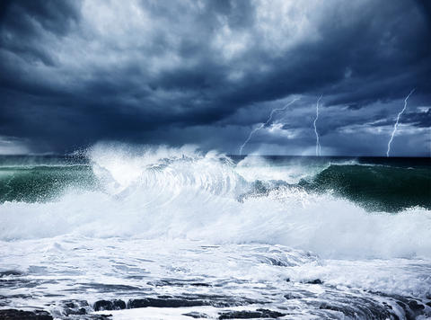 Illustration photo showing a stormy ocean with lightning in a dark blue sky.