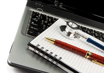 Notatblokk, penn og stetoskop ligg på tastaturet til ein laptop