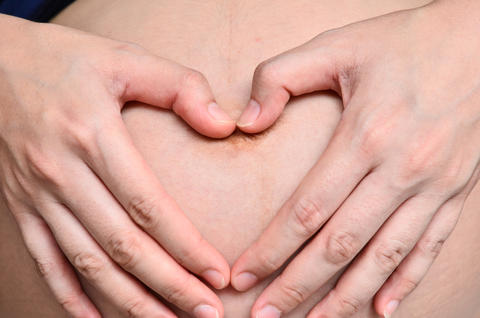 gravid mage og hender som lager hjerte