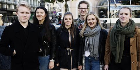 Seks studenter står ved den Blå steinen i Bergen sentrum