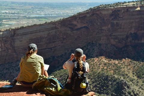 Bildet viser to studenter på ekskursjon i USA. Studentene sitter med ryggen til fotografen og skuer ut over landskapet.