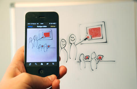 Smarttelefon i forgrunn, tek bilde av illustrasjon på tavle