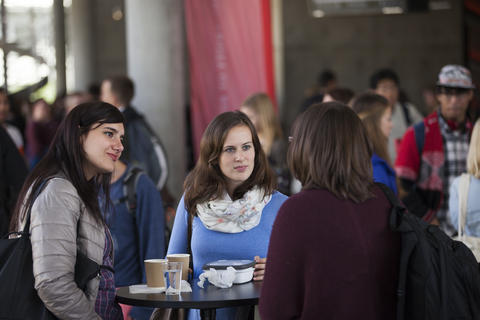 Three female students standing together, discussing