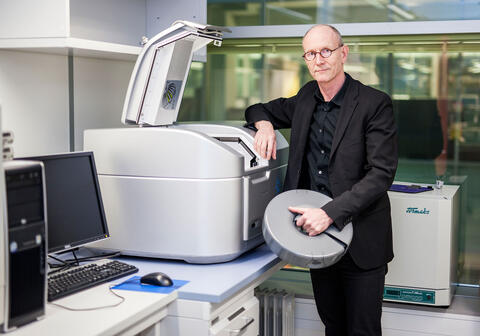 Professor Kalland standing in front of the micro matrix machine in the lab.