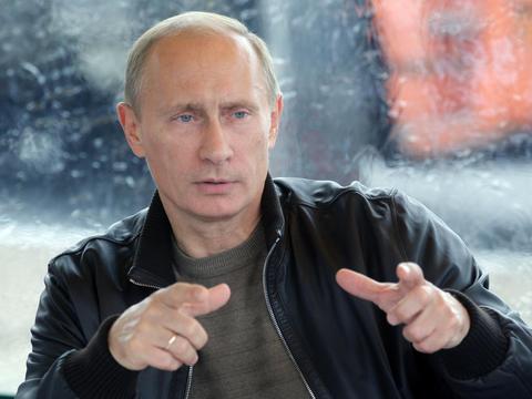 Picture of Russian President Vladimir Putin with hands raised forward and both forefingers pointed forwards.