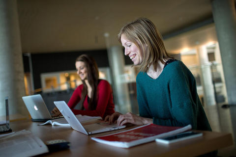 Two female students with computers, smiling