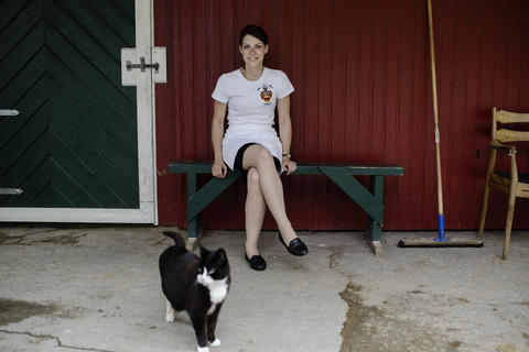 A female student sitting on a bench with a cat at her legs