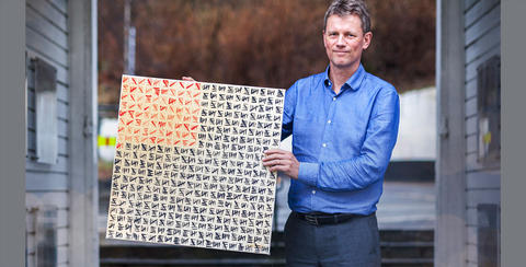 Ole Frithjof Norheim standing, holding a painting.