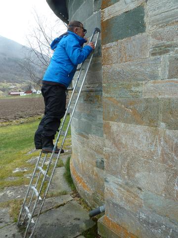 Geolog Øystein Jansen studerer bygningstein av kleber, Hove kyrkje, Vik i Sogn